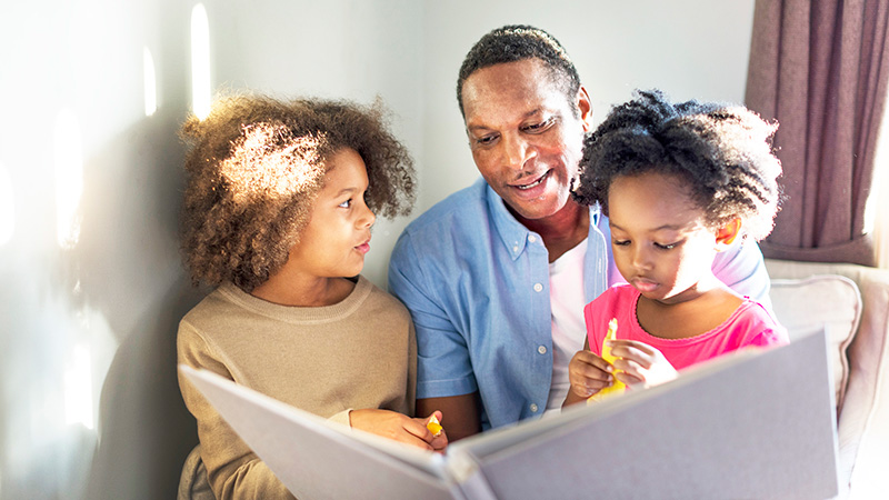 father reading to young daughters