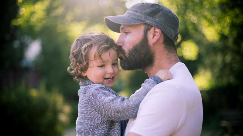 Father kissing his young son's forehead