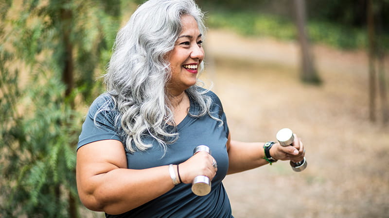 middle-aged woman using free weights outdoors