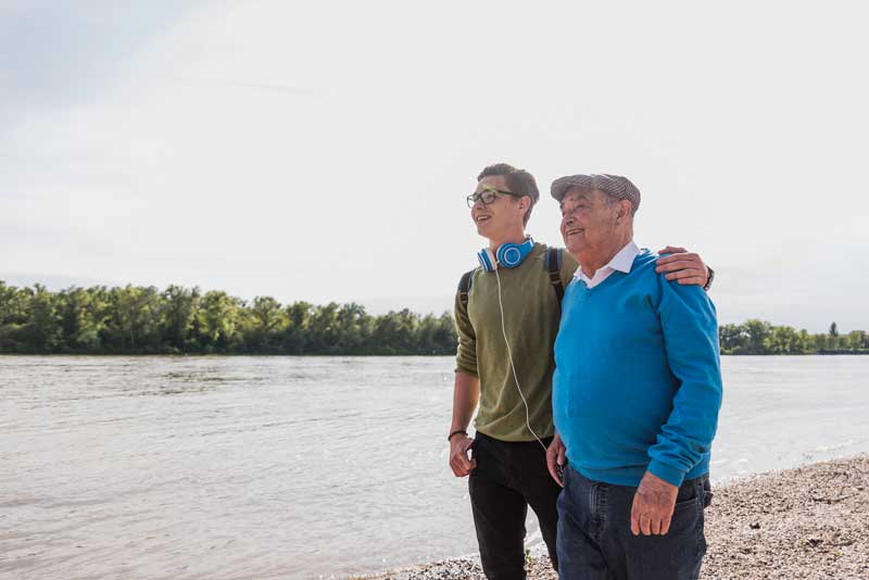 Grandfather and grandson walking by a lake