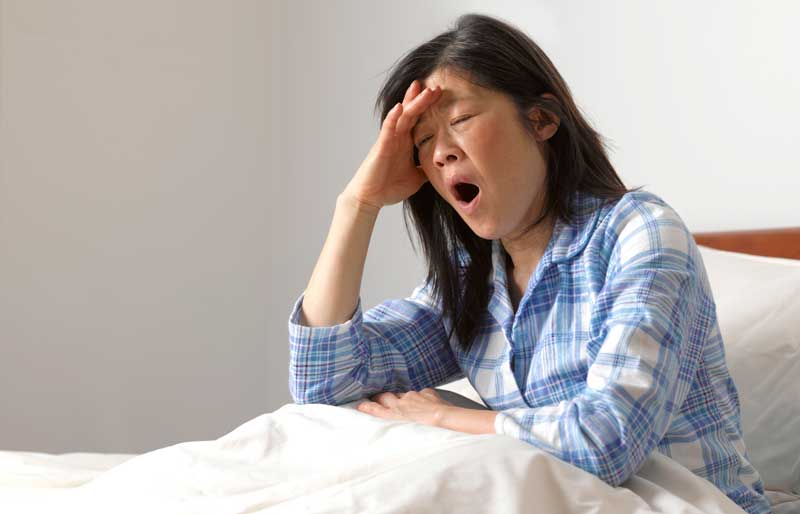 Sleepy woman yawning in her bed