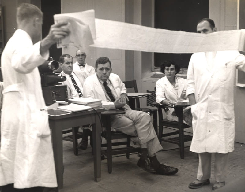 Dr. Eugene Braunwald (seated front left) and Dr. Nina Starr Braunwald (seated right) study an electrocardiogram printout, circa 1963. (Photo courtesy of the Office of NIH History and Stetten Museum)