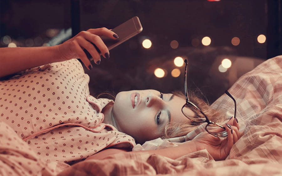 woman using cell phone in bed