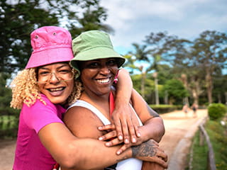 Two women in colorful hats hugging in a park