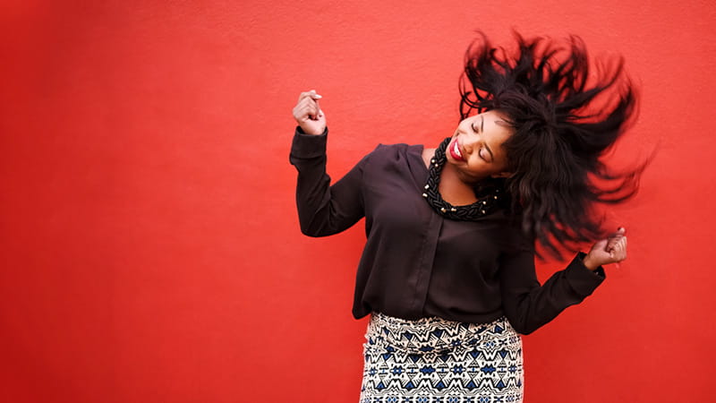 A woman is dancing and shaking her head and hair in front of a red background. A woman is dancing and shaking her head and hair in front of a red background.