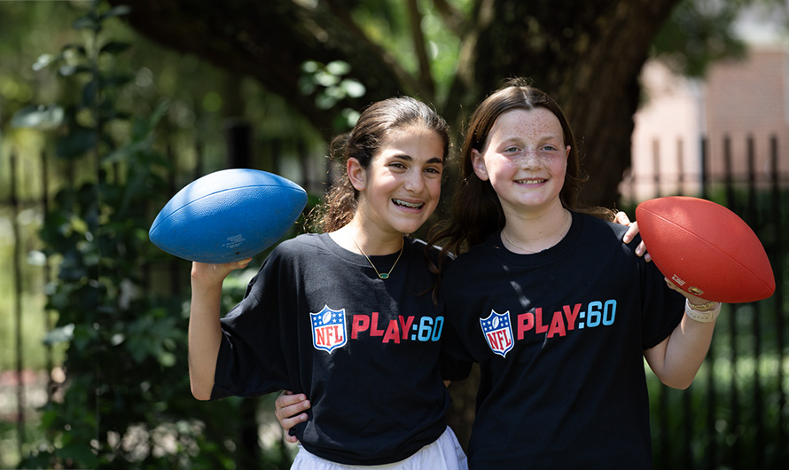 Two cheerful girls holding footballs