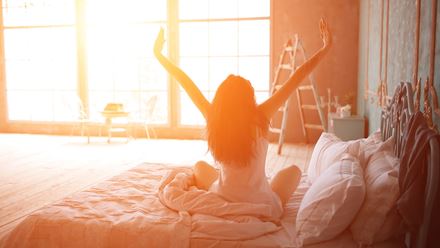 woman stretching out of bed at dawn