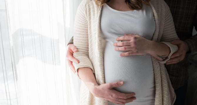 Pregnant woman and partner standing by window