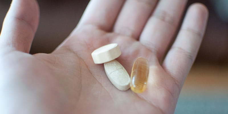 Hand holding multivitamin capsules