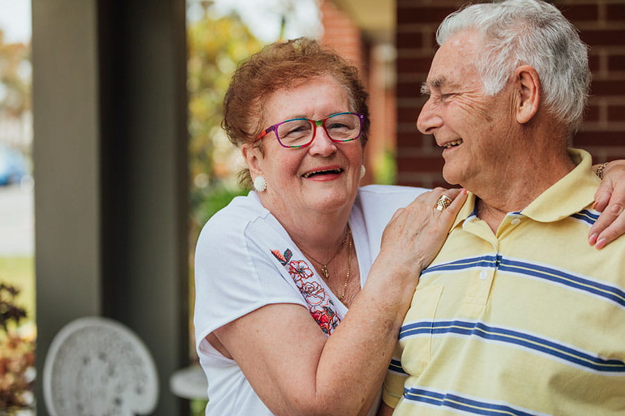 Older couple smiling and hugging outside