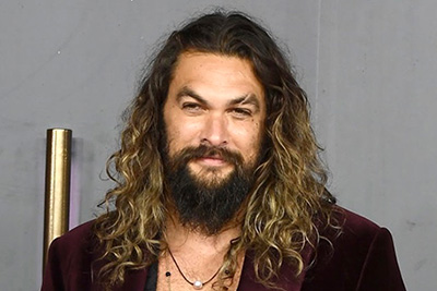  Jason Momoa on a grey background (photo by Jeff Spicer/Getty Images for Warner Bros)