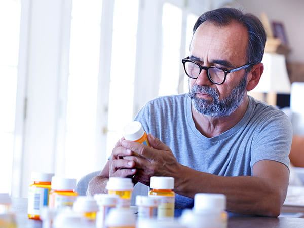 An older Latino man is sitting at a table sorting through prescription medications. An older Latino man is sitting at a table sorting through prescription medications.