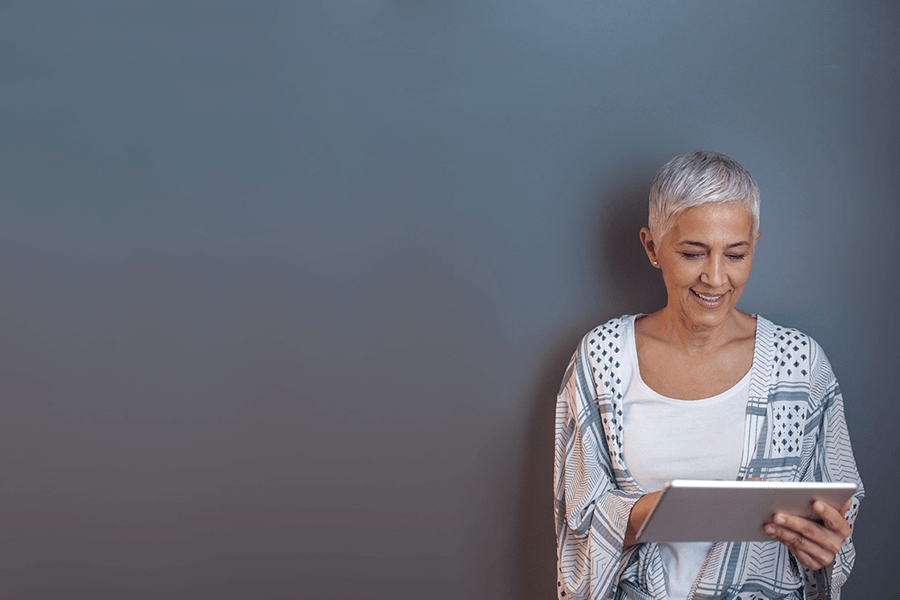 Woman standing against a wall using her laptop